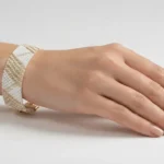 دستبند میوکی سفید با خطوط طلایی روی مچ دست