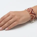 دستبند میوکی نارنجی، زرشکی و کرم با طرح موجی، بسته شده روی مچ دست