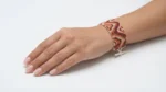 دستبند میوکی نارنجی، زرشکی و کرم با طرح موجی، بسته شده روی مچ دست
