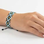 دستبند میوکی سفید و سبز با طرح لوزی بسته شده روی مچ دست