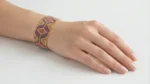 دستبند پهن میوکی با طرح هندسی بنفش، مسی و طلایی، بسته شده روی مچ دست
